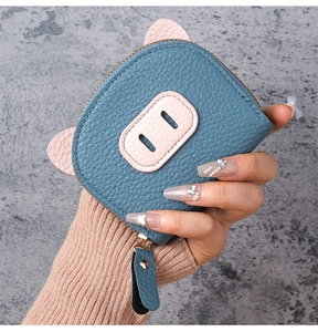 Detail shot of blue leather pig-shaped coin purse with soft pink 3D ears and zipper close