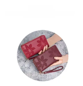 Détail de portefeuilles longs rouge et bordeaux avec gaufrage floral et fermetures éclair