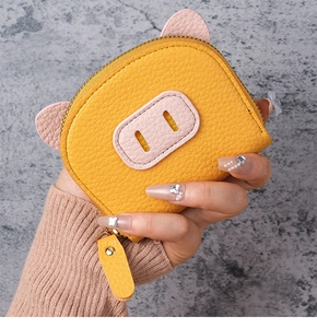 Close-up of yellow pig-shaped mini coin purse with pink ears and textured faux leather
