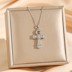 Silver Ankh key necklace with white zircon pavé on champagne silk background