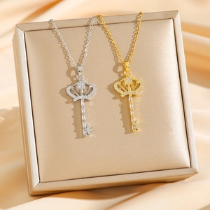 Collier pendentif clé couronne avec zircons en or et argent sur fond de soie douce