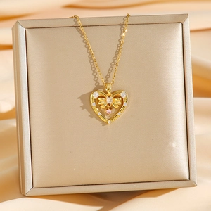Golden heart necklace with pink drop gemstone displayed on champagne silk fabric