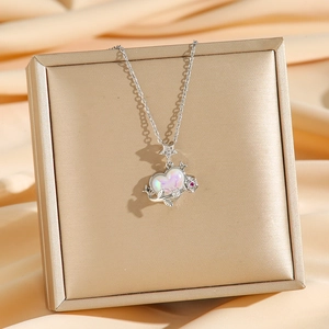Collana in titanio con cuore opale e dettaglio rosa su elegante sfondo di seta champagne