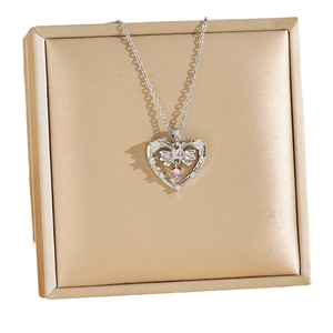 Silver necklace with bow heart pendant and pink crystal on textured jewelry box