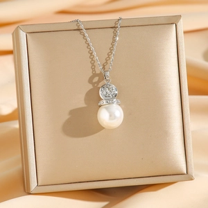 Silberne Engel-Münzkette mit weißem Perlenanhänger auf elegantem Satin-Hintergrund