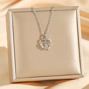 Collier élégant argenté avec pendentif cœur et tour Eiffel sur un coffret à bijoux doré