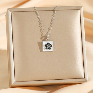 Elegant silver titanium steel necklace with black camellia flower pendant on jewelry box