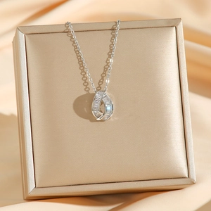 Modern silver necklace with zircon waterdrop pendant on champagne silk background