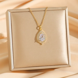 Élégant collier goutte d'eau dorée avec zircons et cristaux sur fond de satin soyeux