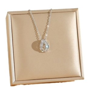 Minimalist silver necklace with geometric zircon pendant displayed on a gold jewelry box