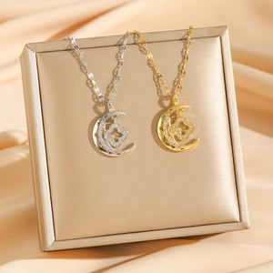 Star and moon necklace with clover pendant in gold and silver on jewelry box