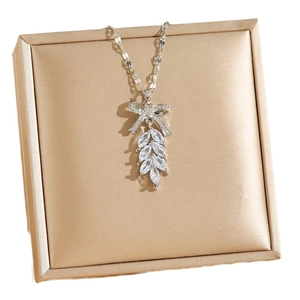 Silver bow necklace with zircon leaf pendant on a satin jewelry box backdrop