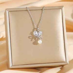 Collier papillon argenté avec zircon et perle blanche sur fond de soie élégante