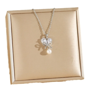 Elegant silver pearl necklace with butterfly zircon pendant on jewelry cushion display