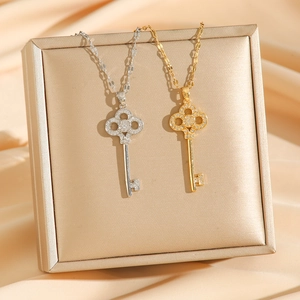 Elegant 18K gold and silver clover key necklaces displayed on silk background