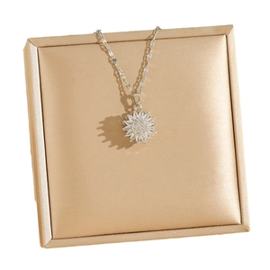 Collier pendentif tournesol rotatif avec zircons posé sur une boîte en soie champagne