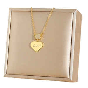 Polished gold heart necklace with Love engraving and crystal buckle on a jewelry display box