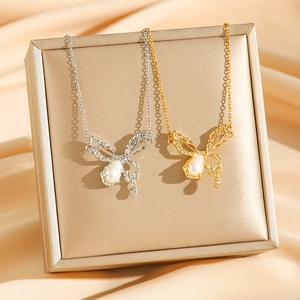 Gold and silver butterfly necklaces with pearl drops on champagne satin background