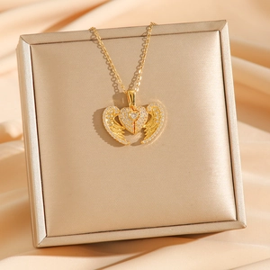 Golden angel wing heart necklace with sparkling crystals on a champagne satin background