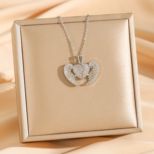 Sparkling angel wing heart necklace with pavé zircons on premium champagne silk display