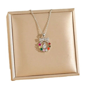 Bow wreath necklace with colorful cubic zirconia and teardrop pendant on jewelry box