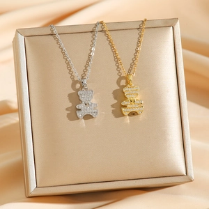 Bear pendants in gold and silver with white zircon pavé on champagne silk display
