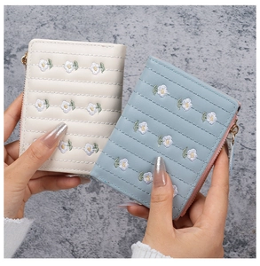 Close-up of beige and blue PU leather wallets with daisy embroidery and gold hardware