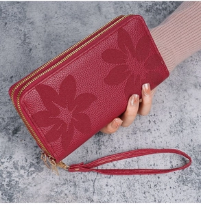 Détail du portefeuille en cuir bordeaux avec gaufrage floral et double fermeture