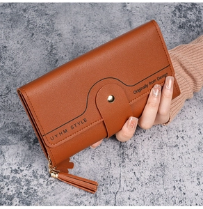 Detailed view of caramel brown lychee leather long wallet with tassel and gold snap button