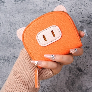 Close-up of orange pig-shaped leather coin purse with gold zipper held in hand