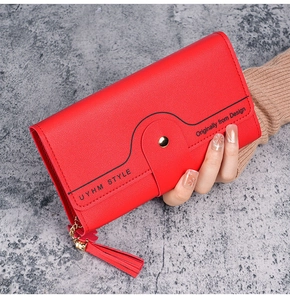 Detailed view of red pebble leather wallet with wave stitching and decorative tassel