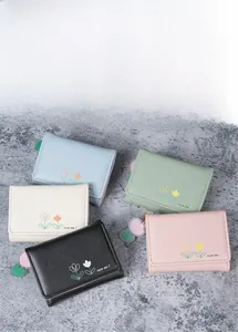 Vue de dessus de petits portefeuilles en cuir aux couleurs pastel et fleurs