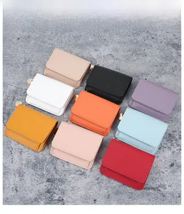 Flat lay of small lychee grain leather card holders in nine vibrant colors with gold hardware
