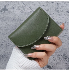 Close-up of small forest green pebbled leather wallet with elegant curved flap