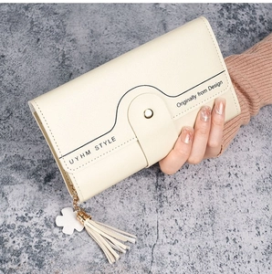 Close-up of beige long wallet with tassel detail and metal snap button closure
