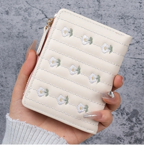 Detail of cream PU leather wallet with daisy embroidery and gold zipper detail