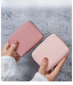 Close-up of small lychee-patterned leather wallets in pink with gold double zippers
