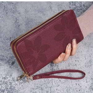 Détail d'un portefeuille long bordeaux avec motif papillon embossé et double fermeture