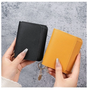 Close-up of black and yellow lychee leather card holders with gold metal rings