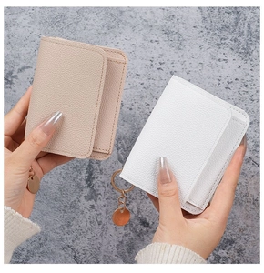 Close-up of pebble leather card holders in beige and white with gold key rings