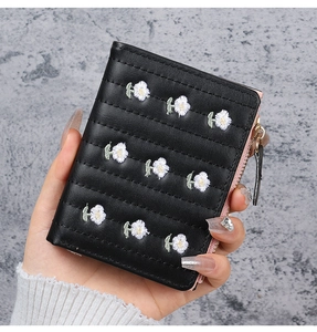 Close-up of black PU leather wallet featuring white daisy embroidery and pink piping detail