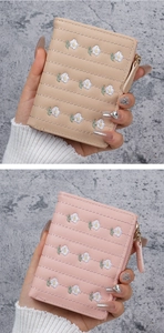 Detail of beige and pink wallets featuring daisy embroidery and zipper pocket