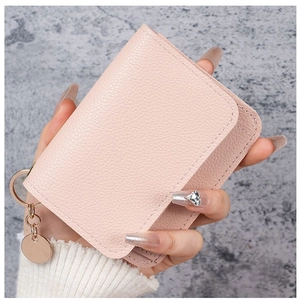 Close-up of pink lychee grain leather card holder with gold ring and round pendant