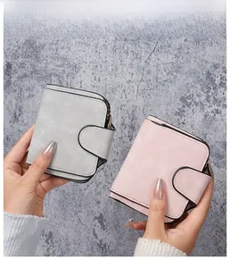 Close-up of minimalist bifold wallets in pink and grey with matte suede texture