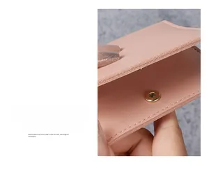 Close-up of slim pink leather card holder with secure metal snap button closure detail