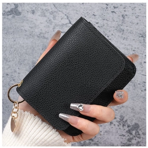 Handheld view of a black pebble leather small wallet with gold ring and clasp detail