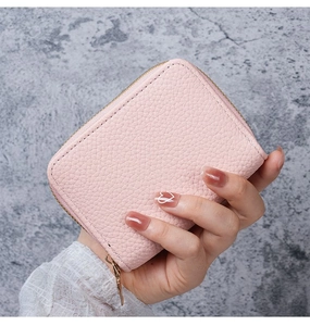 Close-up of pink litchi grain leather wallet with golden zipper detail and fine stitching