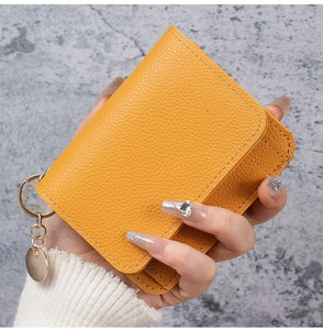 Detailed view of yellow lychee grain leather card holder with gold keychain hardware