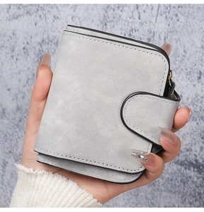 Detailed view of light gray bifold short wallet featuring rounded buckle and black oil edge