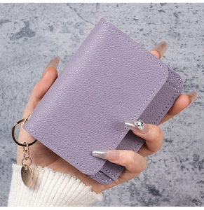 Detailed macro view of a purple litchi grain leather card holder with gold keychain